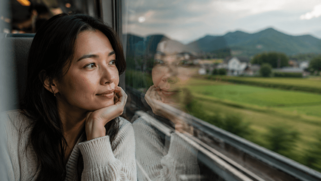 Woman looking through a train window with layered reflections