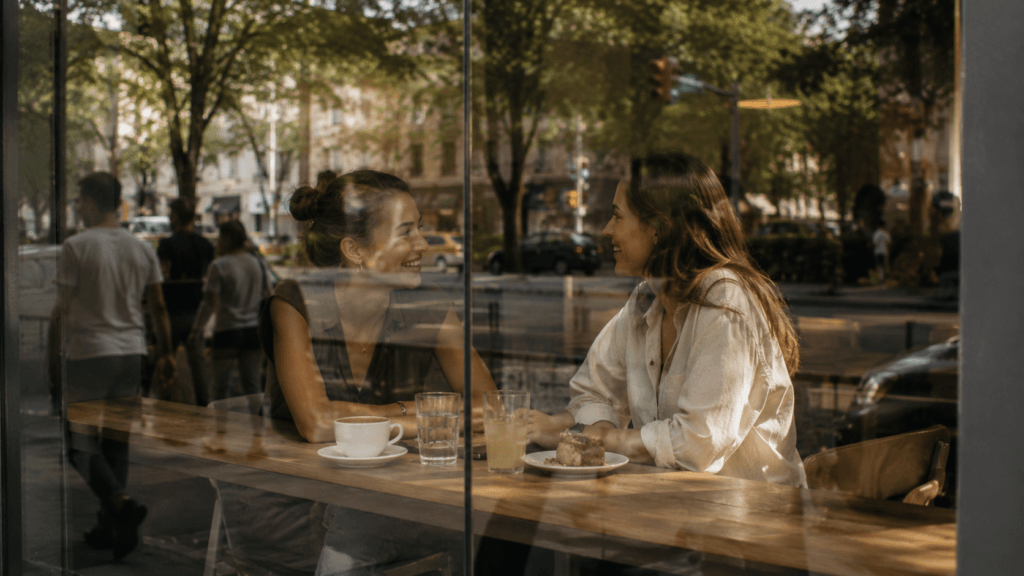 Friends talking through a café window reflection